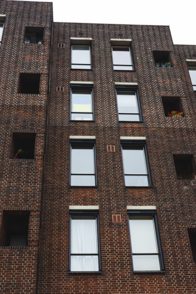 Vertical shot of a modern brick building facade with windows and architectural details.